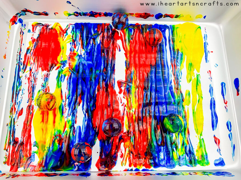 Explore color mixing with this creative painting technique using bouncy balls and a few household supplies! Kids will love this process art activity and you can keep the mess contained using an cake pan or cardboard box. 
